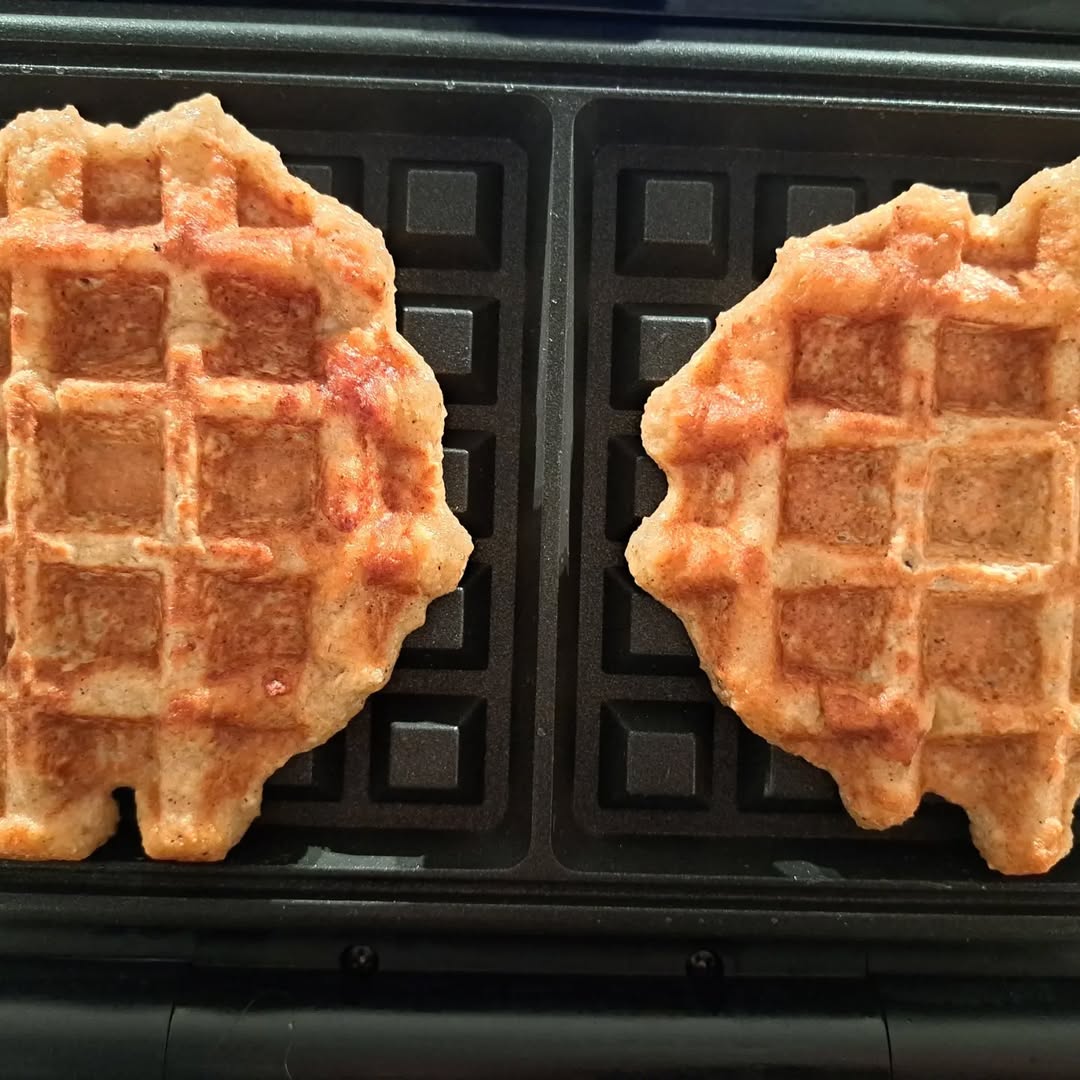 Twee versgebakken wafels in een wafelijzer, klaar om geserveerd te worden